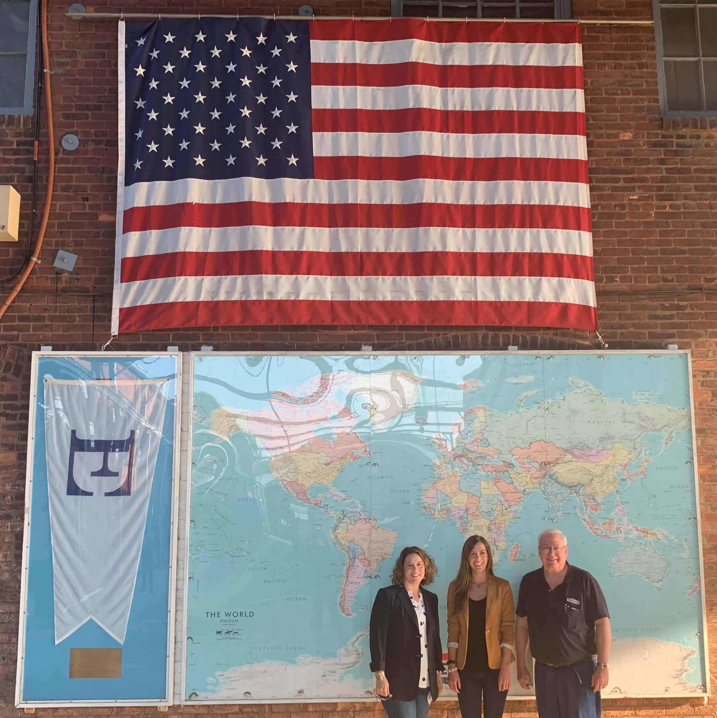 DRMA Government Relations Committee Meet Up - Tayte French Lutz, Jena Powell and Daniel P. French Standing in Front of World Map Under Flag